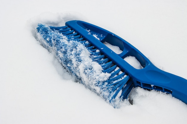 A escova de remoção de azul remove a neve do pára-brisa do carro em um dia de inverno, neve.