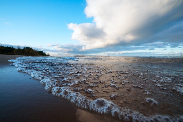 A espuma das ondas na costa arenosa.