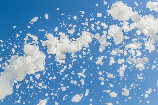 A espuma do sabão voa de um canhão contra o céu