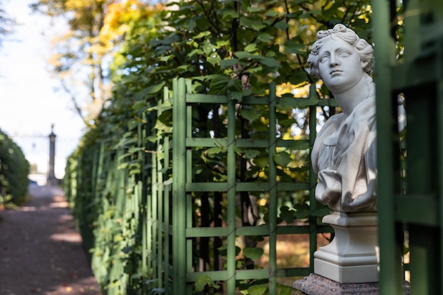 A estátua de uma mulher sensual grega ou italiana da era da Renascença italiana com flores no parque da cidade ganhou as cores douradas do outono.