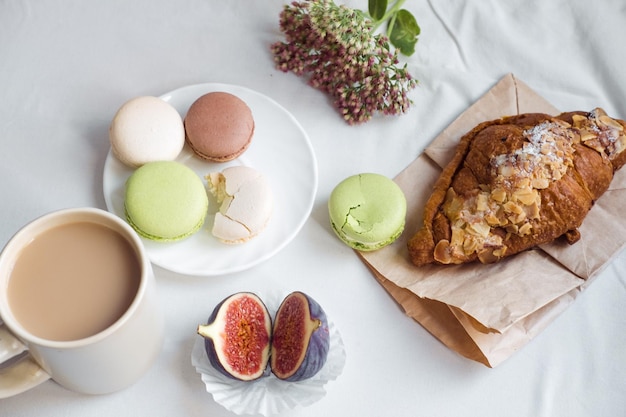 A estética de uma xícara de café representa um grande croissant e macarons em uma vista superior de fundo branco