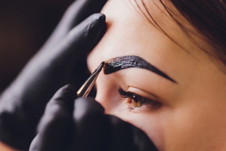 Foto a esteticista- maquiadora aplica hena de tinta nas sobrancelhas aparadas, desenhadas anteriormente, em um salão de beleza na correção da sessão. cuidado profissional para o rosto.