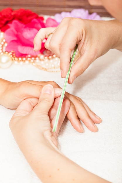 A esteticista polonês unhas do cliente antes de colocar unha polonês