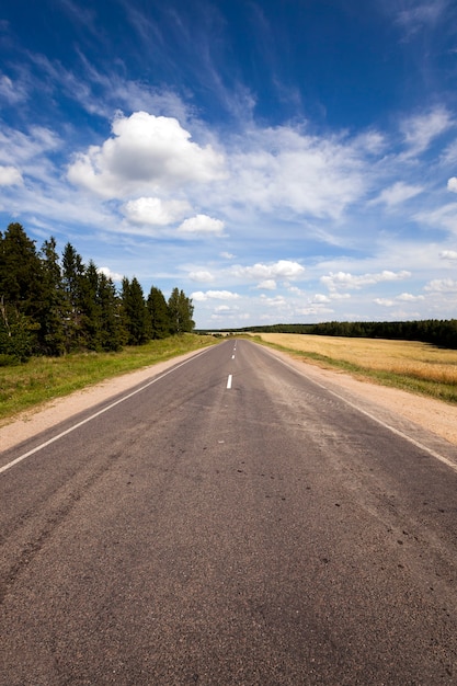 A estrada asfaltada - a pequena estrada asfaltada rural fotografada no verão do ano.