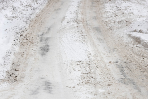 A estrada está coberta de neve com vestígios de pneus de carro. Foto de alta qualidade