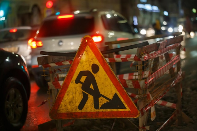 A estrada trabalha à frente sinal na rua da noite de inverno perto do poço