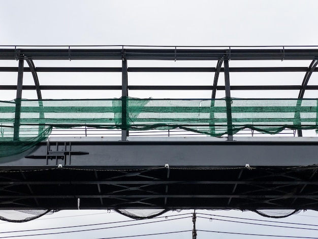 Foto a estrutura metálica inacabada da ponte de caminhadas do céu sob a ponte ferroviária do metrô perto da estação urbana vista frontal com o espaço de cópia