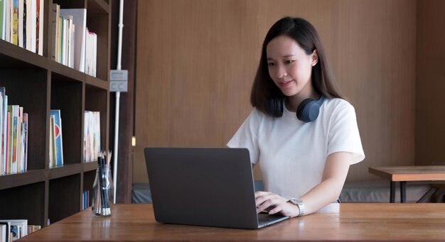 A estudante asiática inteligente se sente satisfeita durante os cursos on-line da Internet e pesquisando informações via laptop em casa