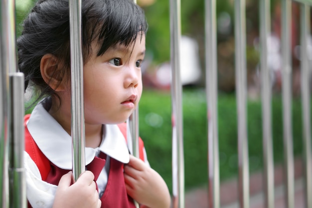 A estudante asiática veste uniforme escolar e vai para a escola e mantém cerca de aço inoxidável