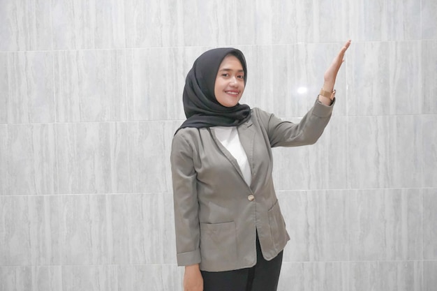 A expressão feliz de uma mulher indonésia asiática de hijab vestindo uma camisa branca e um casaco cinza