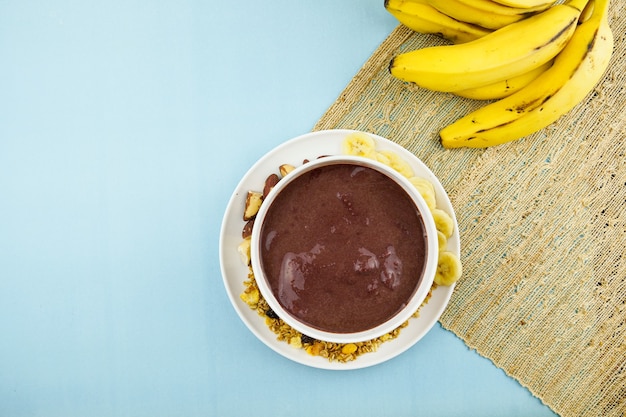 AÃƒÂ§ai brasileño en un cuenco blanco con plátano, granola y castañas.