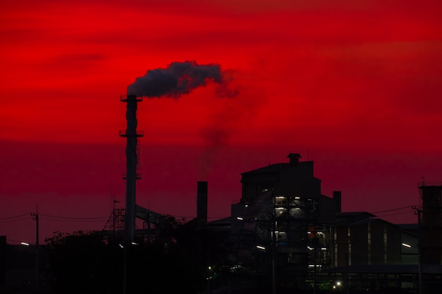 A fábrica liberou a chaminé de fumaça no pôr do sol O aquecimento global