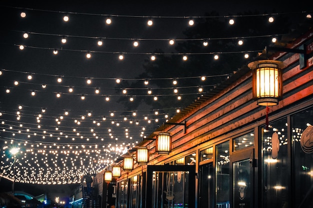A fachada de um pequeno café asiático decorado com lanternas e guirlandas Muitas luzes brilham no ni