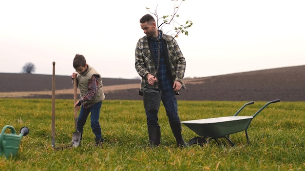 A família amigável plantando uma árvore no campo verde