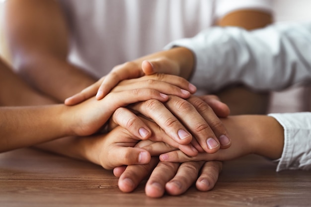 A família dá as mãos juntas na mesa