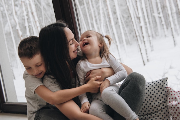 A família está sentada à janela, olhando para a floresta de inverno. bom espírito de ano novo. manhã de pijama.