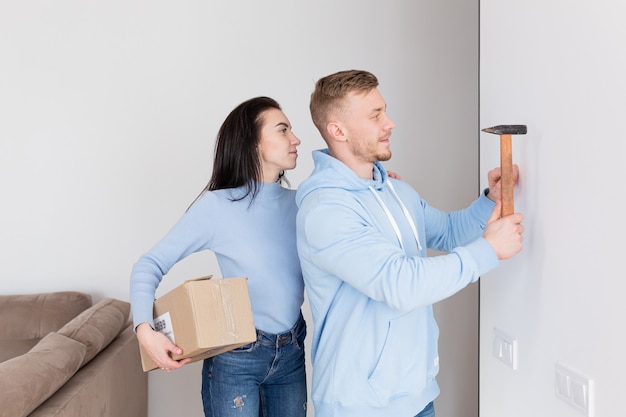 A família feliz mudou-se para um novo apartamento, o homem pendura um quadro na parede