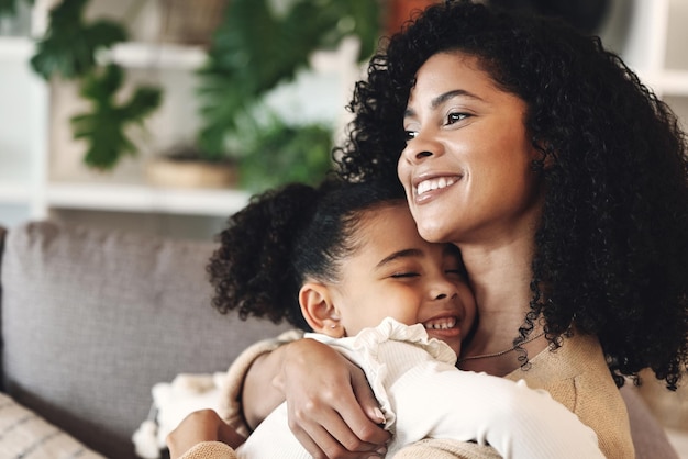 Foto a família negra ama e abraça a menina e a mãe em um sofá feliz e relaxa em sua casa juntos mãe, filha e abraçada em um sofá alegre e contente enquanto compartilha um doce momento de união