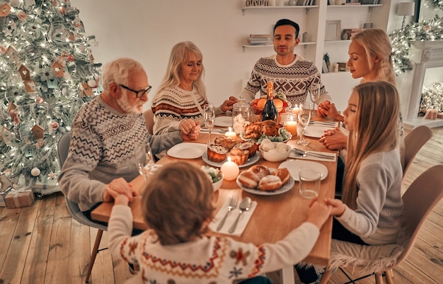 A família rezando na mesa de natal