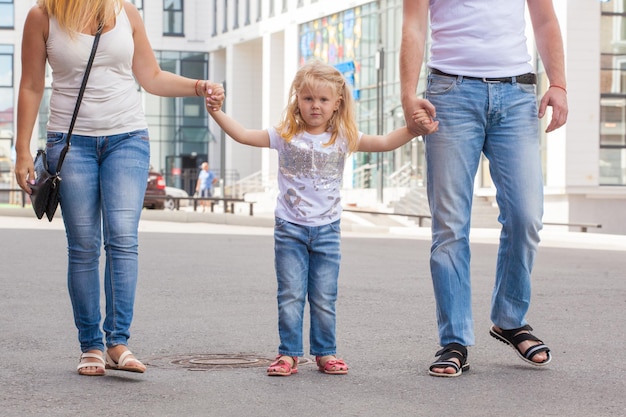 A família sai para passear. menina segurando a mão dos pais