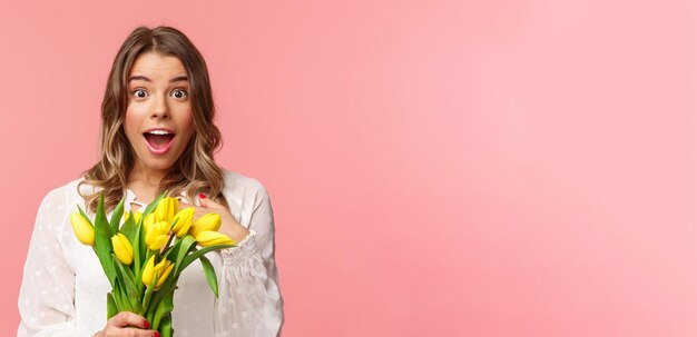 A felicidade da primavera e o conceito de celebração aproximado de uma jovem loira surpresa e admirada em branco