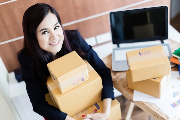 A felicidade e a alegre mulher asiática fazem compras on-line