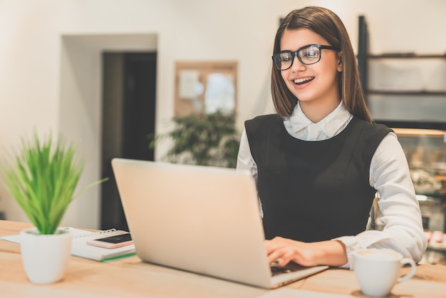 A feliz empresária de óculos trabalhando com um laptop