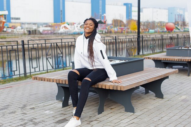 A feliz mulher afro-americana no parque em um banco