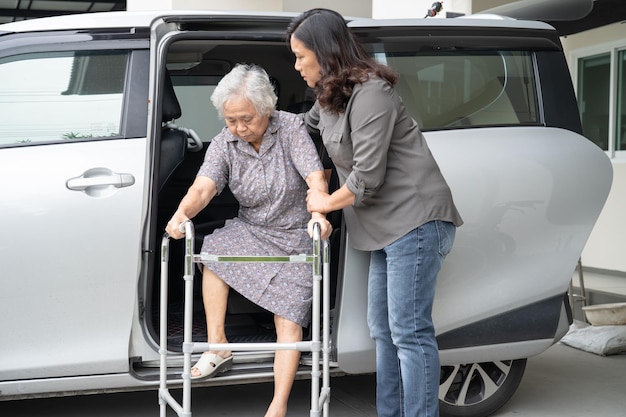 A filha cuidadora ajuda e apoia a paciente idosa asiática ou idosa que prepara para sair do carro