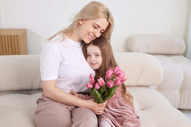 A filha da criança parabeniza a mãe dando flores tulipas Férias em família Abraço