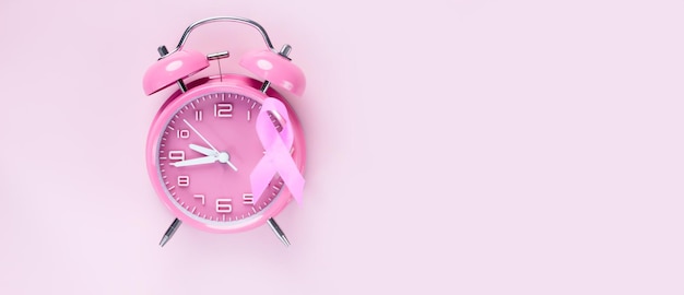 A fita de laço rosa é anexada ao despertador rosa para incentivar uma campanha de câncer de mama