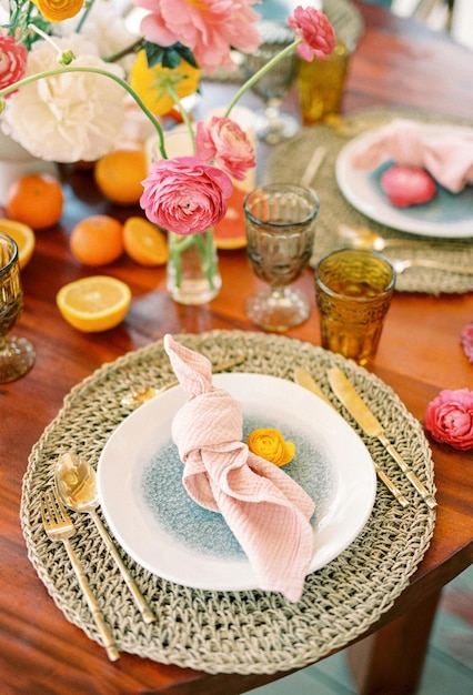 A flor amarela fica em um prato ao lado de um guardanapo em um tapete de vime em uma mesa festiva