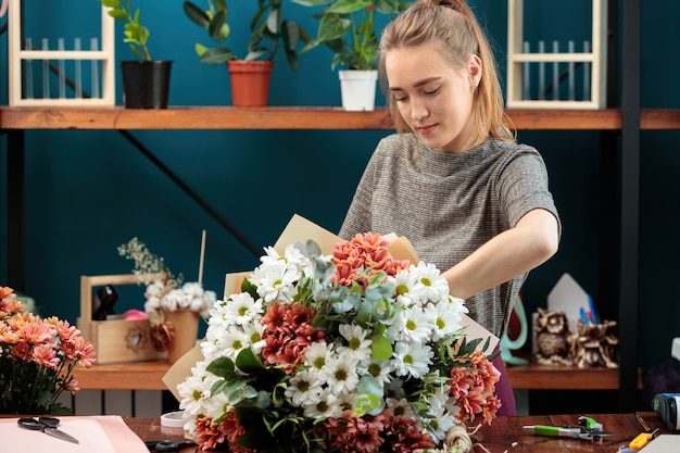 A florista faz um buquê de crisântemos multicoloridos. Uma jovem adulta trabalha com entusiasmo.