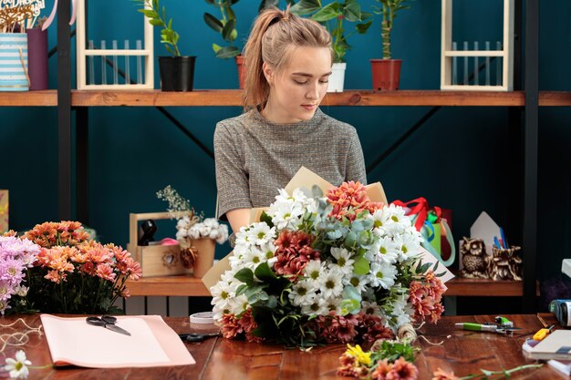 A florista faz um buquê de crisântemos multicoloridos. Uma jovem adulta trabalha com entusiasmo.