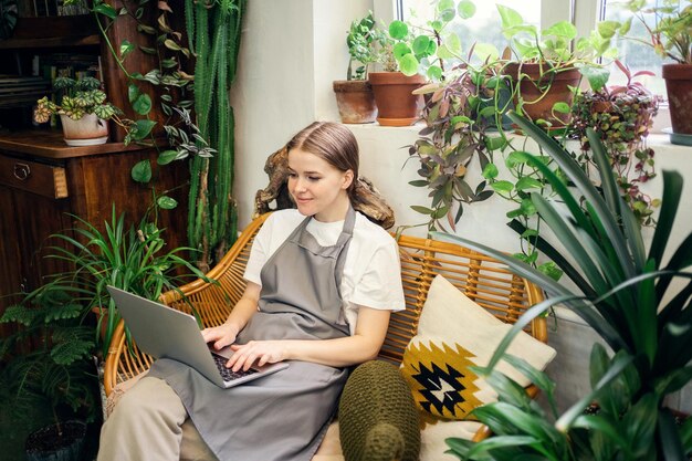 A florista vende flores e plantas para a casa no estúdio A mulher jardineira usa