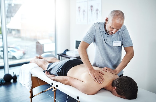 A fonte de sua dor está nas costas Foto de um fisioterapeuta tratando um paciente