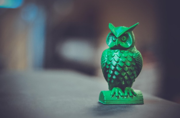 A forma verde na forma de uma pequena coruja criada em uma impressora d fica na superfície de um escuro