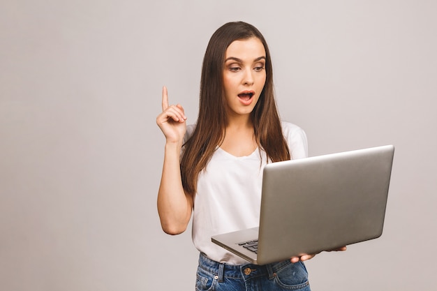 A foto de uma jovem alegre usando o computador laptop tem uma ideia.