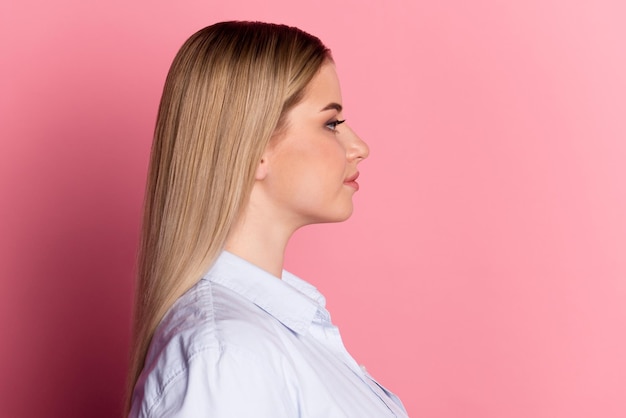 A foto do lado do perfil da jovem parece um espaço vazio concentrado inteligente isolado sobre o fundo de cor rosa