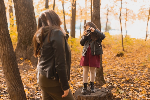 A fotógrafa infantil tira fotos de uma mãe no parque na arte fotográfica de passatempos de outono e