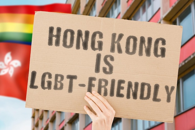 A frase "Hong Kong é LGBT-Friendly" em um banner na mão dos homens com bandeira LGBT borrada no fundo. Relações humanas. diferente. Diversos. liberdade. Sexualidade. Problemas sociais. Sociedade