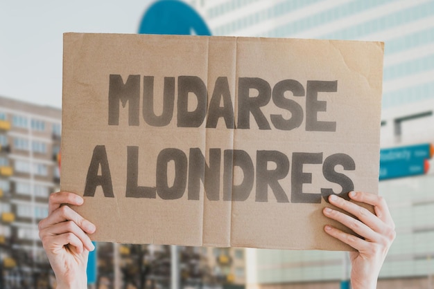 A frase mudando para londres em um banner de papelão na mão de homensindústria contratação de trabalho contratação recrutamento empregar recruta contrato regras de transferência processo de operação