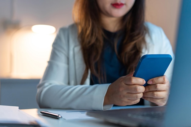 A funcionária do escritório trabalhando até tarde no escritório enquanto mandava mensagens de texto para o telefone