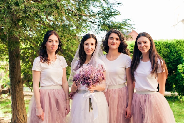 A futura noiva com lindas amigas em pé no parque de verão