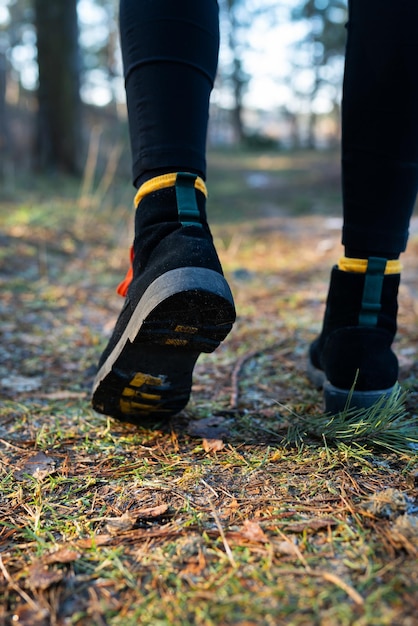 A garota caminha pela floresta fechada de sapatos no contexto do conceito de trekking e caminhadas na floresta