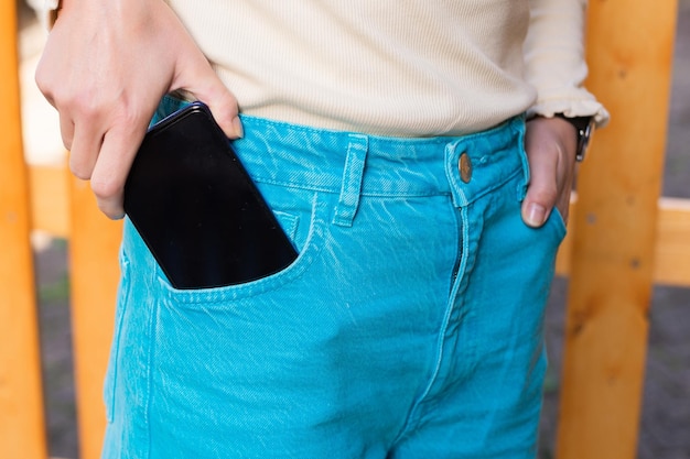 A garota coloca o telefone no bolso da frente de sua calça jeans azul
