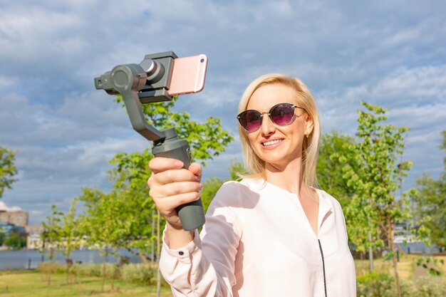 A garota com o telefone no estabilizador lidera o videoblog. ela se leva para a câmera smartphone