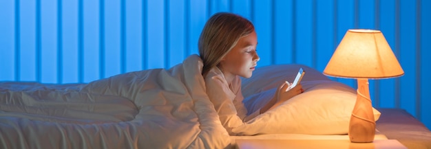 Foto a garota com um telefone estava deitada na cama tarde da noite