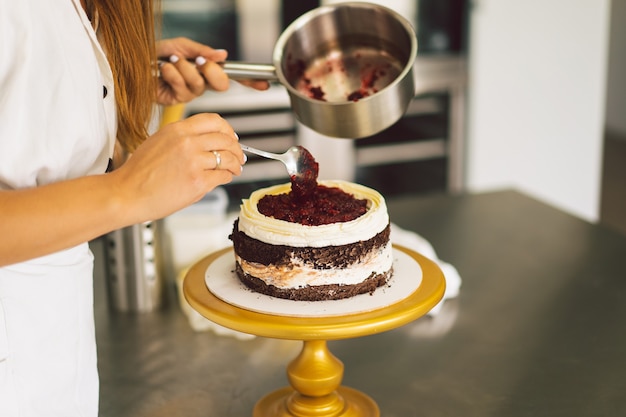 Foto a garota da confeiteira está preparando um biscoito de bolo com creme branco e bolos de chocolate para cozinhar