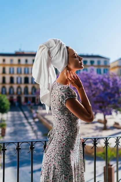 A garota de férias no hotel, com prazer inala o ar na varanda aberta